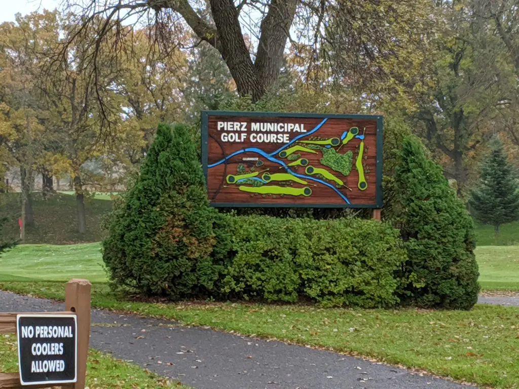 The carved entrance sign at Pierz Municipal Golf Course, showing a painted map of the holes